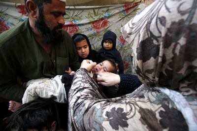 A health worker administers polio vaccine drops to a child during a door-to-door vaccination campaign in Peshawar, Pakistan. EPA
