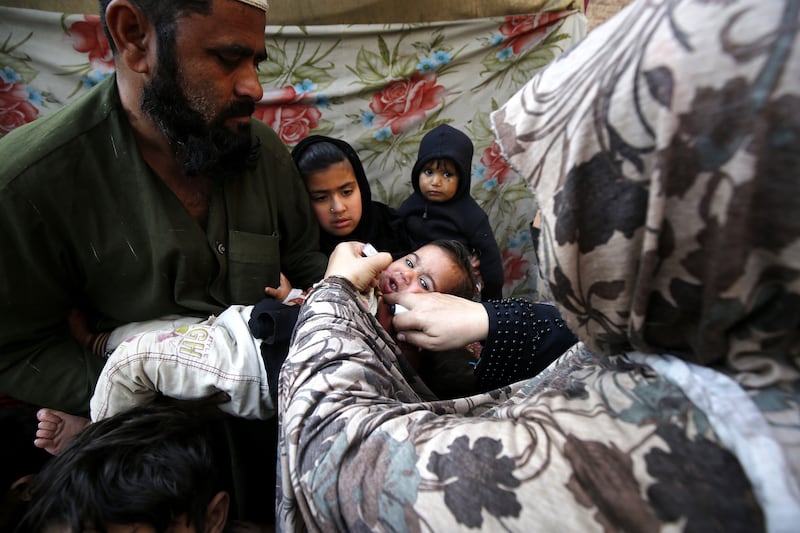 A health worker administers polio vaccine drops to a child during a door-to-door vaccination campaign, in Peshawar, Pakistan. EPA