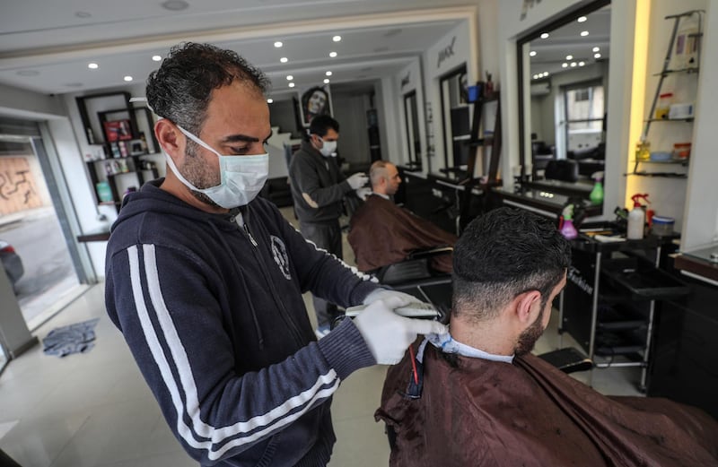A Palestinian barber wears protective a facemasks and hand gloves as a precaution against the spread of the Covid-19 coronavirus. EPA