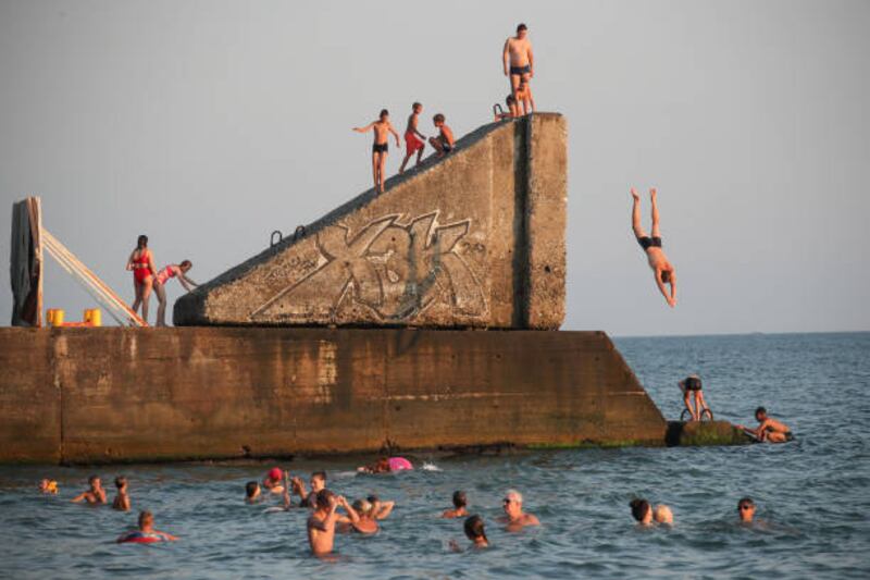 Bathers jump off a harbour wall into the sea in Mamaika, a neighbourhood in the seaside resort of Sochi, on Russia's Black Sea coast, on August 3. Getty