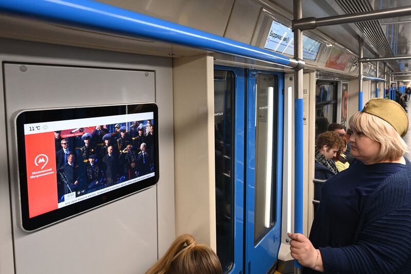 Commuters watch a broadcast of the parade on a metro train in Moscow. AFP