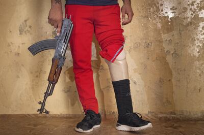 Hassam Naeem, 22, a former Iraqi Hashd Al Shaabi fighter, got injured during a military operation against the Islamic State. Amputee and jobless, Naeem poses with a Kalashnikov rifle at his parent's house, in Basra, a major city in south Iraq. Photo by Sebastian Castelier