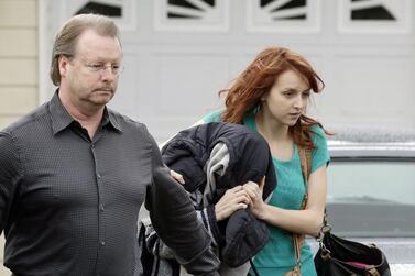 A woman believed to be Amanda Knox, centre, is hidden under a jacket while being escorted from her mother’s home to a car by family members on Thursday. AP Photo  