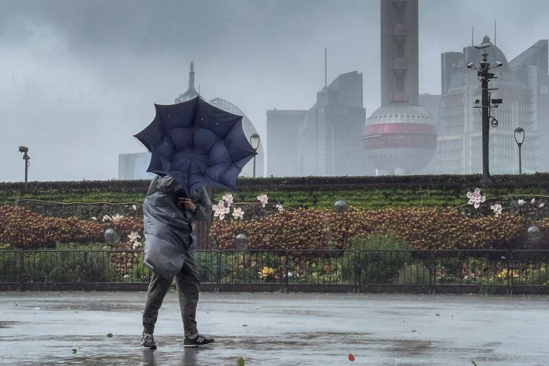 A pedestrian struggles to control their umbrella along the Bund in Shanghai.