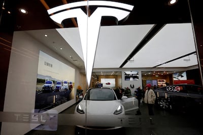 Visitors check a Tesla Model 3 car next to a Model Y displayed at a showroom in Beijing. Reuters