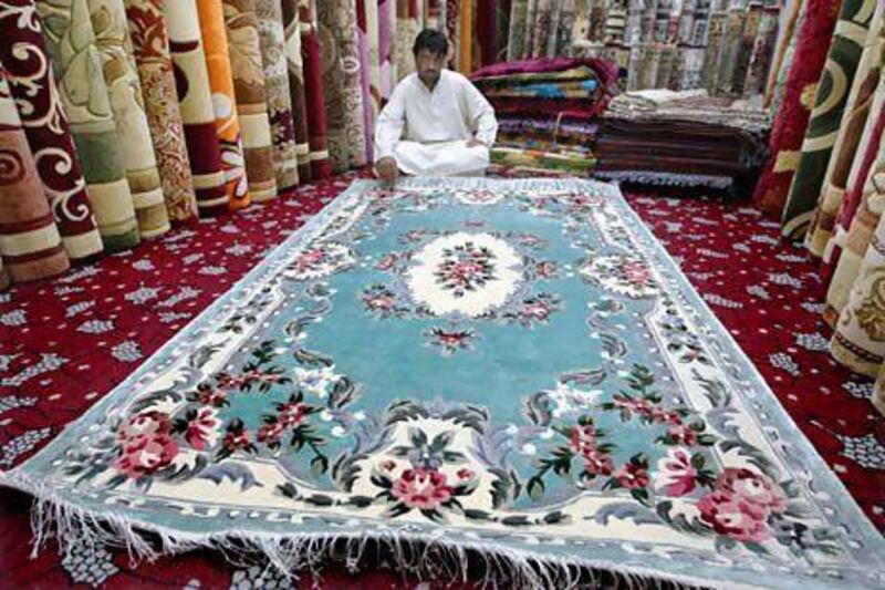 Abdullah Khan, a trader, sits with an Iranian carpets at the Abu Dhabi carpet souq. Stephen Lock / The National