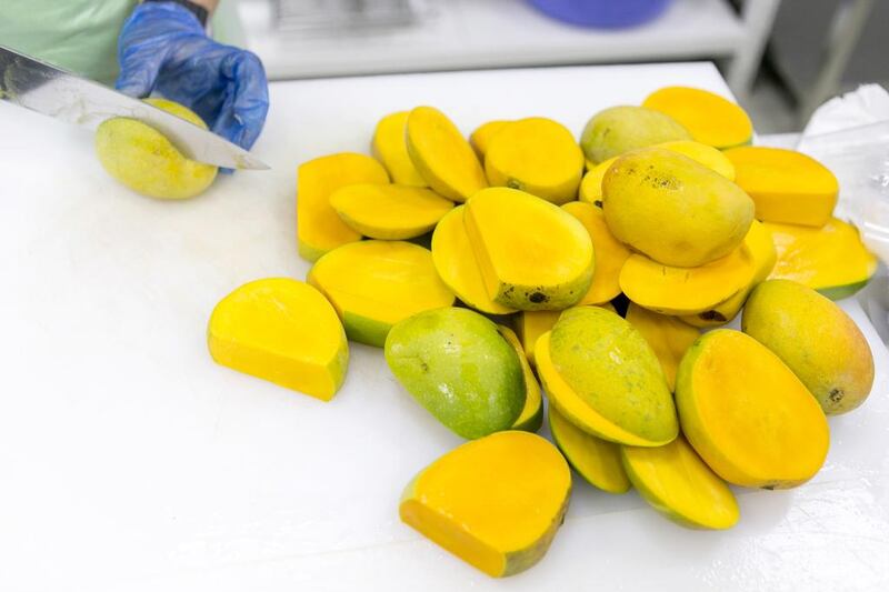 Delivery frequency can be varied from daily to bi-weekly shipments. Above, a Fruitful day staff cuts mangoes for delivery to clients. Reem Mohammed / The National