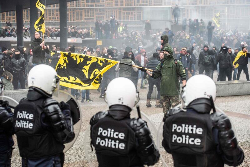 TOPSHOT - Demonstrators clash with Belgian riot police during a march in Brussels on December 16, 2018 called by the right-wing Flemish party Vlaams Belang and a dozen of organisations against the UN Marrakech global compact on migration, signed last week by the Belgian Prime Minister.  Brussels' Mayor forbade the venue of this march but State council ruled against that decision and the march was authorized. A counter march of Solidarity is also planned.   - Belgium OUT
 / AFP / Belga / JONAS ROOSENS
