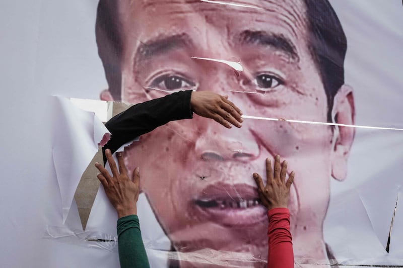 Counter-protesters in Jakarta fix a ripped banner of Indonesia's President Joko Widodo as demonstrators demanded his impeachment, the rejection of the general election results and the removal of members of the General Election Commission. AFP