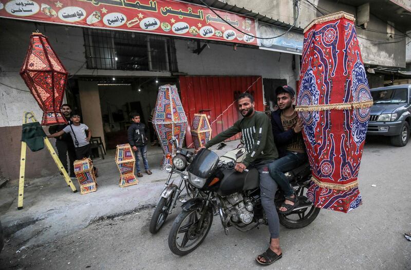 Palestinian men ride a motorcycle while carrying a newly made traditional "fanous" lantern, a decoration used to celebrate the start of the Muslim holy month of Ramadan, in Khan Yunis in the southern Gaza Strip.  AFP