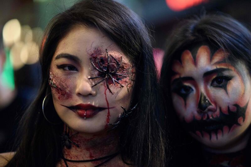 Revellers wearing Halloween make-up pose for a photo as they walk past bars and restaurants in the popular nightlife district of Itaewon in Seoul.  AFP
