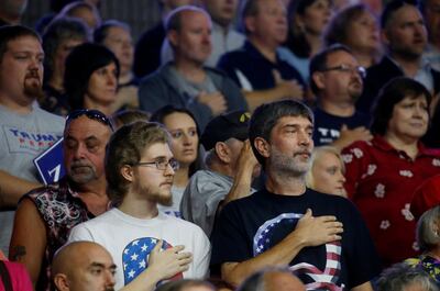 Supporters stand for the National Anthem while sporting shirts with prominent "Q"s symbolic of the QAnon movement, while waiting for U.S. President Donald Trump to speak at a Make America Great Again rally at the Civic Center in Charleston, West Virginia, U.S., August 21, 2018. Picture taken August 21, 2018. REUTERS/Leah Millis