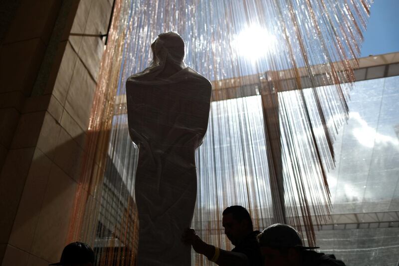 Workers wheel an Oscars statue. Reuters