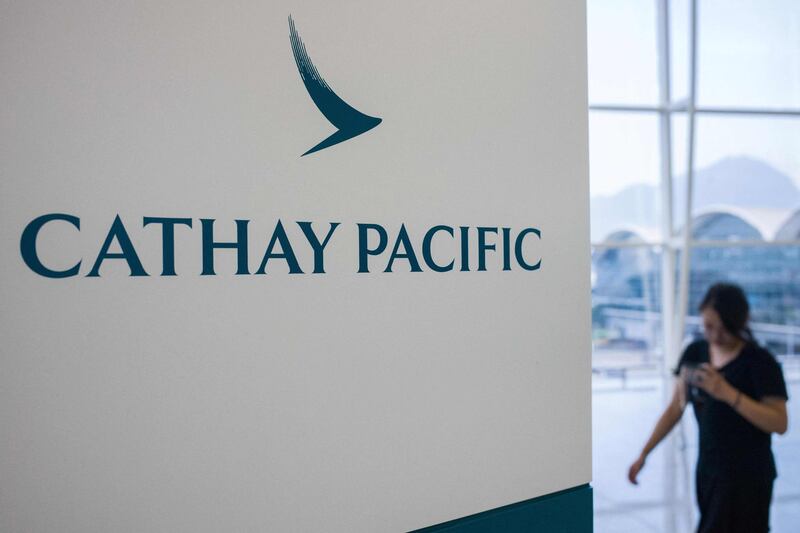 (FILES) This file picture taken on August 7, 2018 shows a woman walking past a Cathay Pacific Airways sign at Hong Kong's international airport. Hong Kong carrier Cathay Pacific said on March 10, 2021 it suffered a 2.8 billion USD loss in 2020 as the coronavirus pandemic hammered its business. / AFP / Anthony WALLACE

