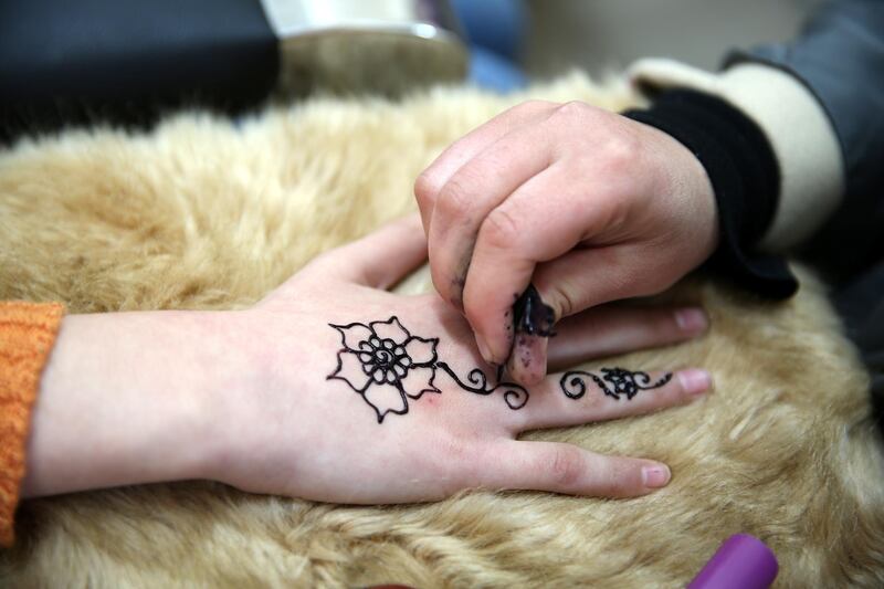 A flower design is drawn on a girl's hand by Palestinian henna tattoo artist Samah Sidr, at her shop in the West Bank city of Hebron. EPA