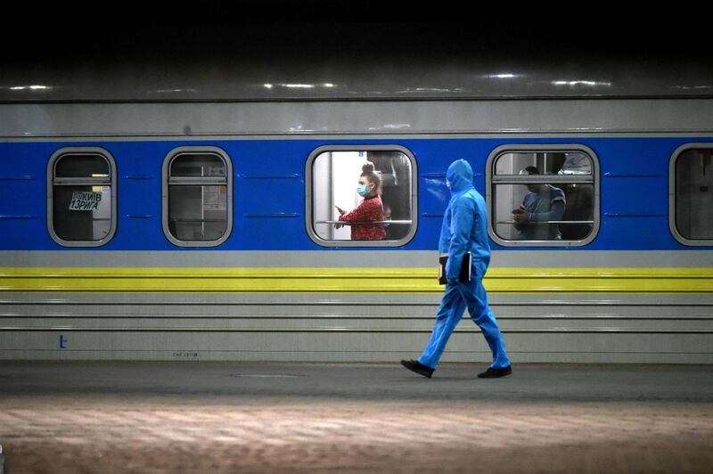 A passenger looks out the window as a medical worker walks past her carriage of a train with Ukrainians evacuated from Riga at a railway station in Kiev.  AFP