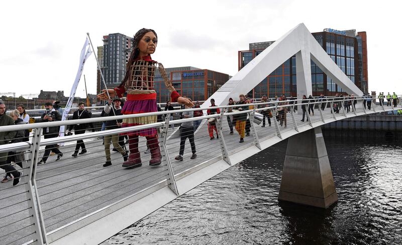 Little Amal, a giant puppet depicting a Syrian refugee girl who has walked across Europe, crosses Tradeston Bridge over the River Clyde in Glasgow. AFP