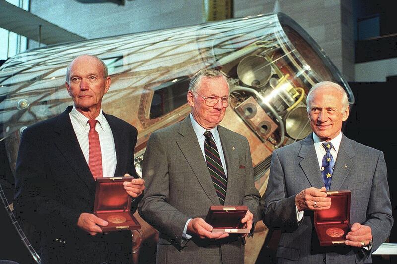 The crew of Apollo 11 Michael Collins (L), Neil Armstrong (C) and Buzz Aldrin stand in front of the Apollo command module Columbia after US Vice President Al Gore awarded them the Samuel P. Langley medal 20 July, 1999 at the National Air and Space Museum in Washington, DC.  Armstrong was the first man to step on the moon 30 years ago 20 July 1969 followed by Aldrin while Collins remained in the orbiting command module.     AFP PHOTO/Joyce NALTCHAYAN (Photo by JOYCE NALTCHAYAN / AFP)