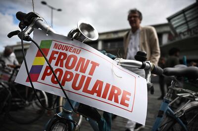 A supporter the leftist Nouveau Front Populaire coalition stands by a placard at a bicycle rally in Bordeaux, south-western France. AFP