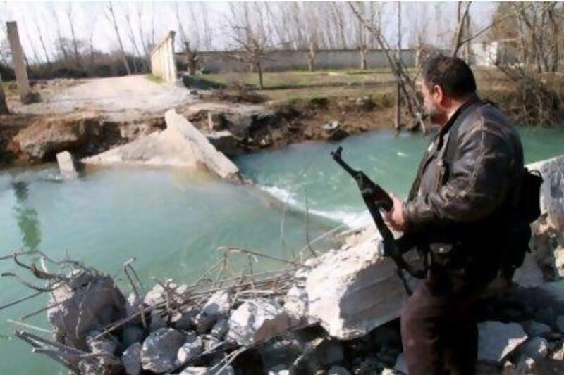 A Syrian fighter stands at the destroyed Al Adra bridge in Rableh, in the area of Qusayr, Homs province. Syrian forces bombed the bridge used as a main escape route to evacuate the wounded and refugees to Lebanon, a monitoring group said.