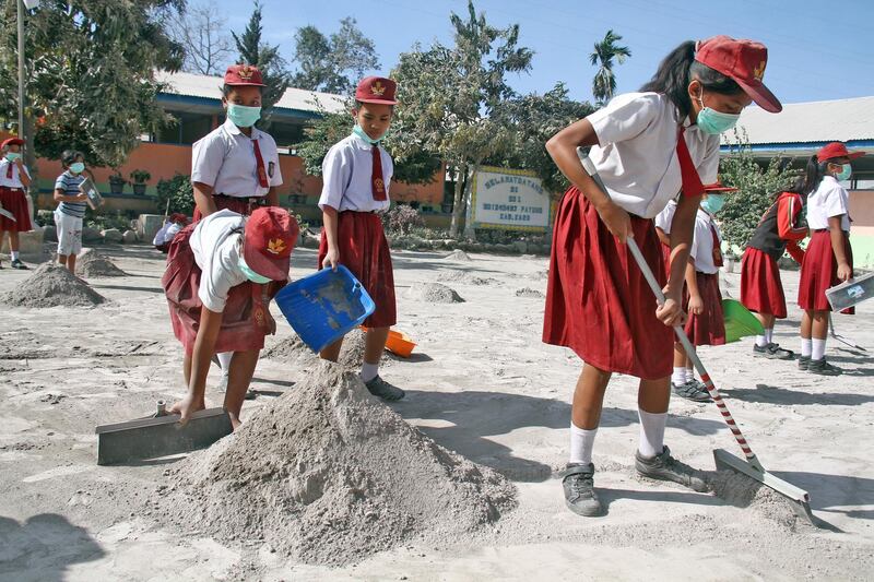 Students clean their school yard from ash after the Mount Sinabung volcano erupted on Monday at Payung village in Karo, North Sumatra. Antara Foto / Ahmad Putra / via Reuters