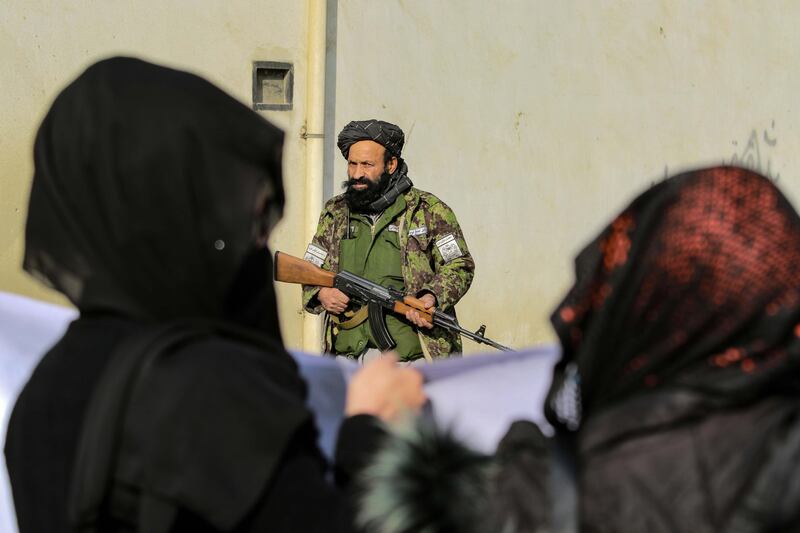 Taliban soldiers stand guard as women carry placards during a rally in Kabul, Afghanistan. All photos: EPA
