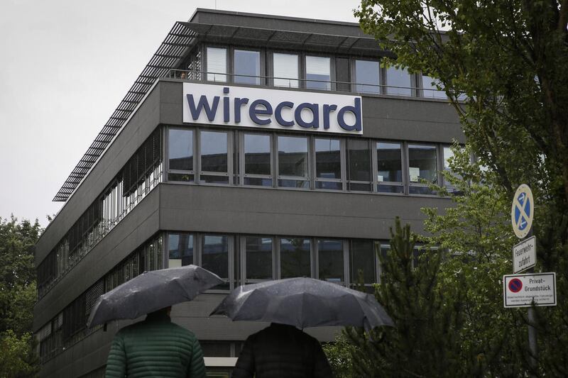 Pedestrians shelter under umbrellas as they walk towards the Wirecard AG headquarters in the Aschheim district of Munich, Germany, on Friday, June 19, 2020. Wirecard shares continued their free-fall after the two Asian banks that were supposed to be holding 1.9 billion euros ($2.1 billion) of missing cash denied any business relationship with the German payments company. Photographer: Michaela Handrek-Rehle/Bloomberg