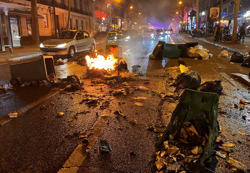 A driver passes  burning rubbish bins in Paris on Monday night. Reuters