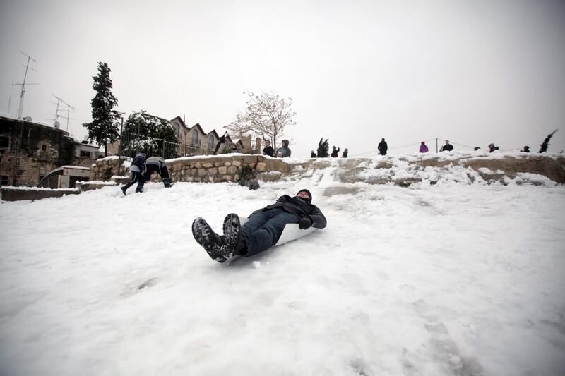 A Palestinian man slides on snow in the old city of Jerusalem on January 10, 2013. Jerusalem was transformed into a winter wonderland after heavy overnight snowfall turned the Holy City and much of the region white, bringing hordes of excited children onto the streets. AFP PHOTO/AHMAD GHARABLI

