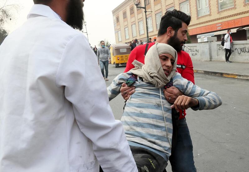 A protester is helped after Riot police fired tear gas during clashes on Rasheed Street in Baghdad. AP Photo