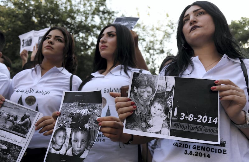 Iraqi Yezidi women hold placards with pictures of victims of the 2014 invasion of their region by the Islamic State (IS) group, a day ahead of commemorations at the Temple of Lalish, in a valley near the Kurdish city of Dohuk, about 430km northwest of the Iraqi capital Baghdad, on August 2, 2019. - Of the 550,000 Yazidis in Iraq before the Islamic State (IS) group invaded their region in 2014, around 100,000 have emigrated abroad and 360,000 remain internally displaced. Roughly 3,300 Yazidis have returned from IS captivity in the last five years, only 10 percent of them men. (Photo by SAFIN HAMED / AFP)