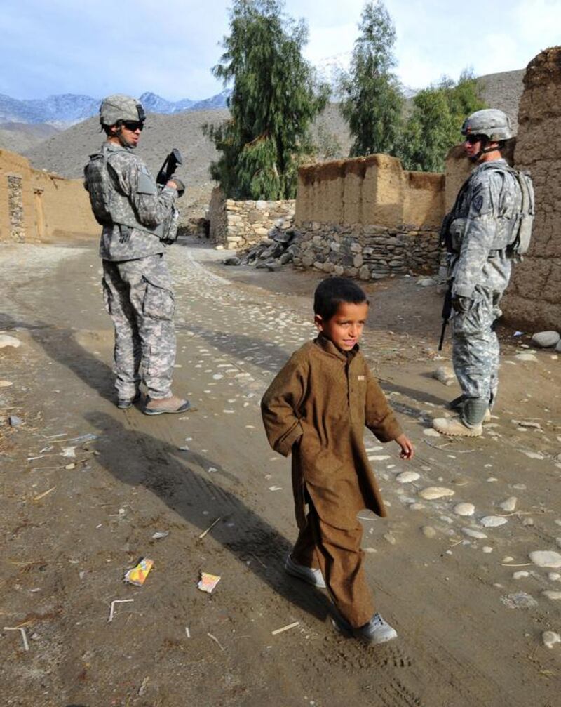 An Afghan child walks past US soldiers in Afghanistan. Kim Jae-Hwan / AFP