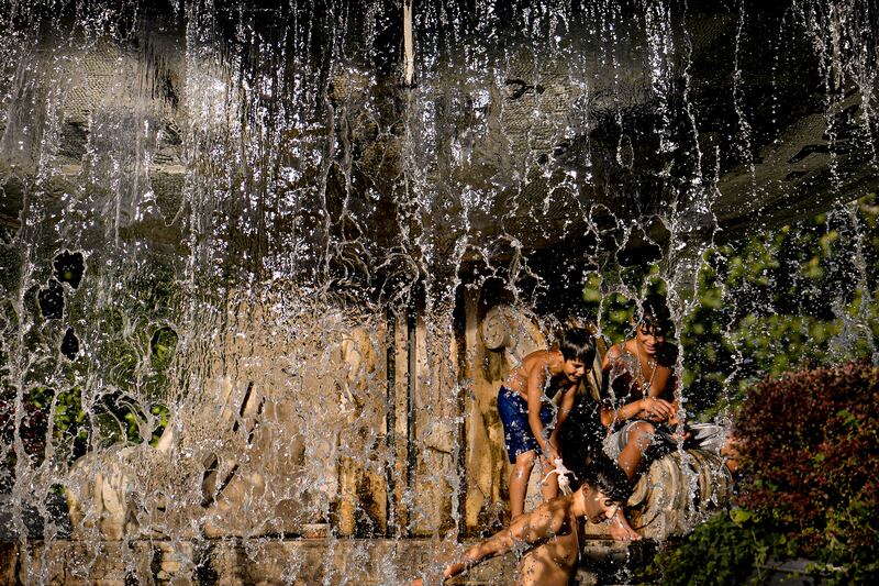 Boys cool off in a city fountain before sunset in Bucharest.  Romania's national weather institute has forecast a heatwave that is spreading throughout Europe and is set to affect the country over the next few days. AP