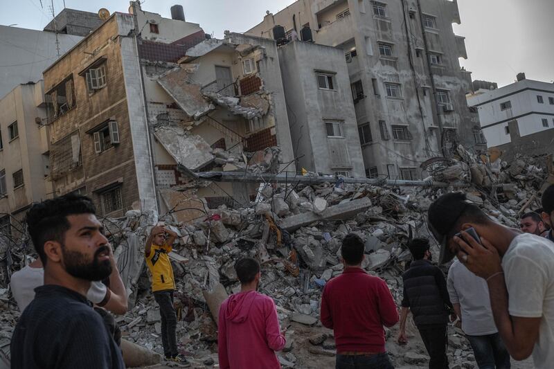 People pass and look at rubble from a previously destroyed building by an air strike as a ceasefire came into effect in Gaza City. Getty Images
