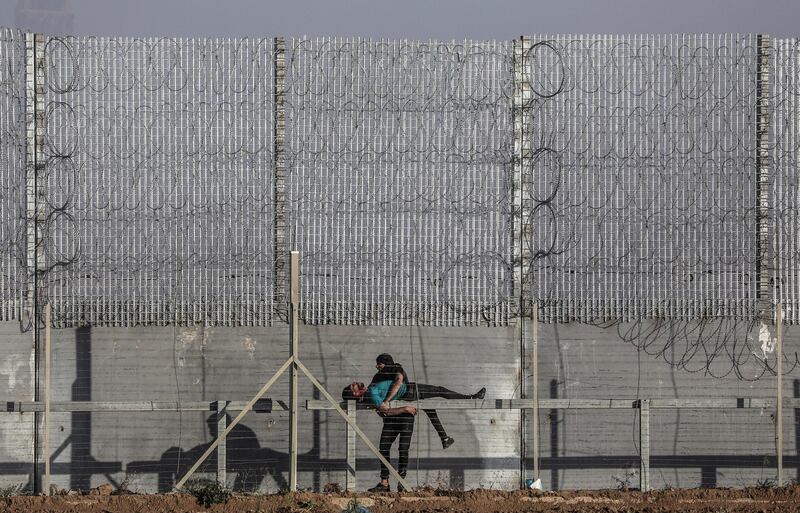 A Palestinian protester tries to help a wounded comrade who appears to be seriously injured, after he was allegedly shot by Israeli sniper, during the clashes after Friday protests near the border between Israel and Gaza Strip, eastern Gaza Strip.  EPA