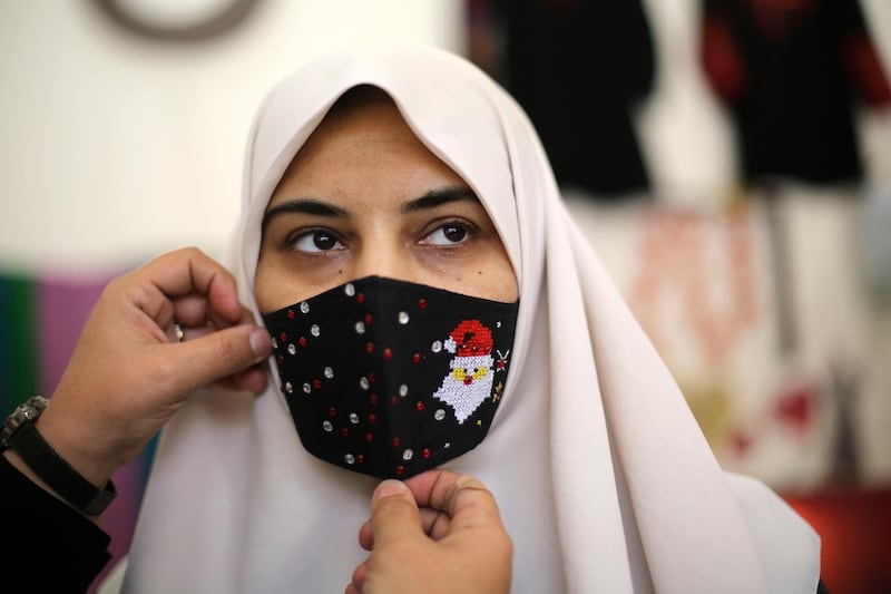A Palestinian woman tries a Christmas-themed mask in Gaza City. AFP
