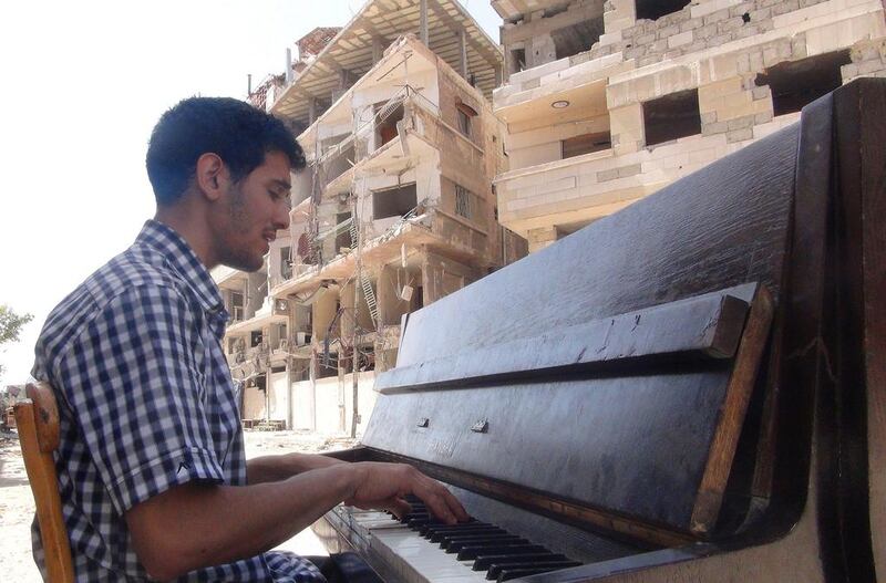 Aeham Al Ahmad, a former resident of Damascus' Yarmouk Palestinian refugee camp, playing the piano in the middle of the street near destroyed buildings in the southern Damascus suburb before his piano was burned by etremists.Rami Al Sayed/AFP Photo


