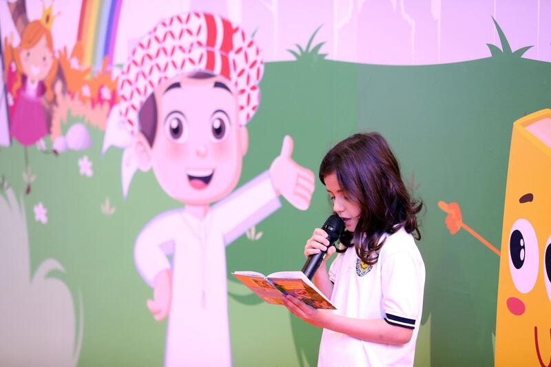 Sharjah, United Arab Emirates - April 18, 2019: A young visitor reads from her book at Sharjah children's reading festival. Thursday the 18th of April 2019. Expo Centre, Sharjah. Chris Whiteoak / The National