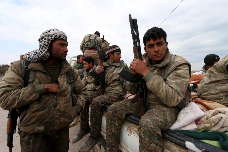 Kurdish People's Protection Units (YPG) fighters carry their weapons while riding on the back of a pick-up truck in Qamishli, Syria. Rodi Said / Reuters