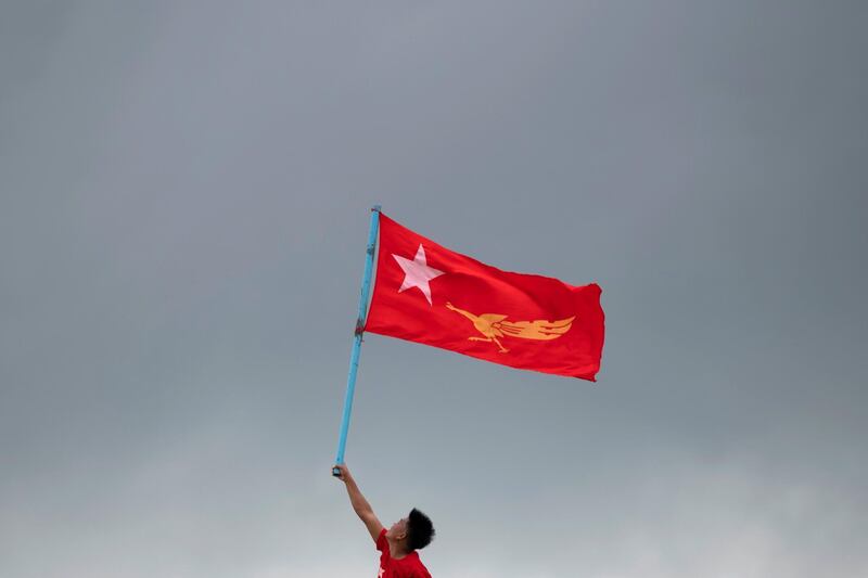 An NLD supporter holds a flag on the top of a boat as he takes part in a rally in the Yangon river. Reuters