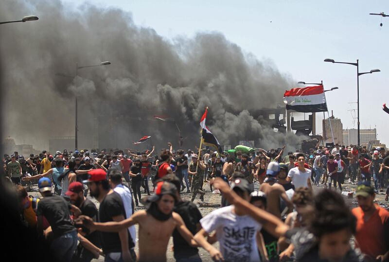 Iraqi protesters run for cover as they clash with security forces on Al Jumhuriyah in the capital Baghdad, following an anti-government demonstration.  AFP