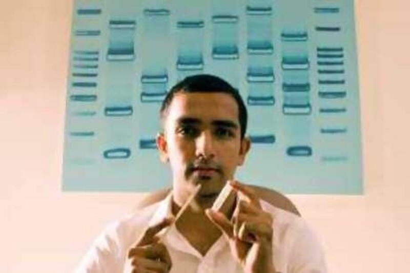 DUBAI - December 21, 2008 - Junaid Faruq, co-founder of DNA-DX, holds a swab and a file of saline solution used in collecting a person's DNA that will be used to make a photographic image of their DNA like the one on Faruq's wall in his home in Dubai, December 21, 2008. (Photo by Jeff Topping/ The National )
