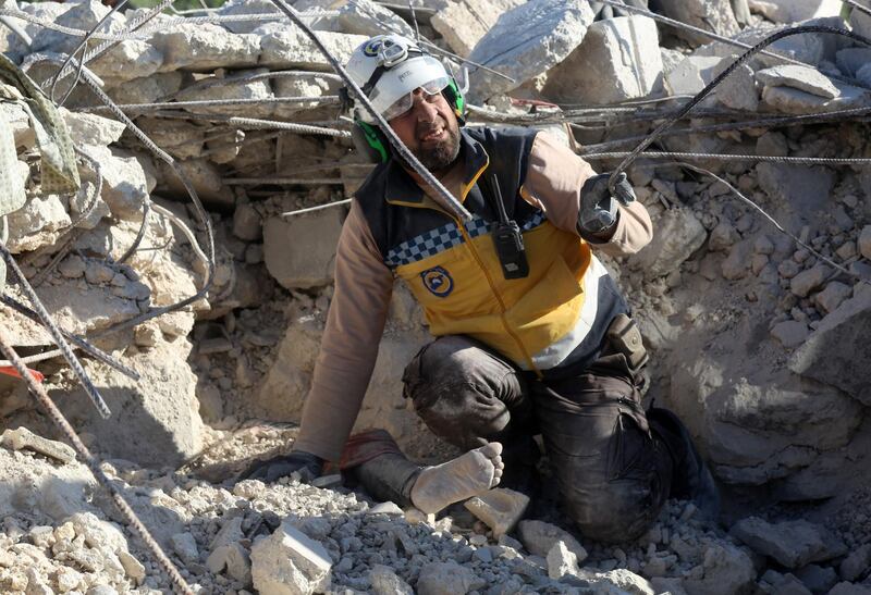 A member of the Syrian Civil Defence (White Helmets) reacts as he prepares to help remove the body of a woman burried under the rubble of a building, who was reportedly killed during shelling by government and allied forces in the village of Rakaya Sijneh, in the southern countryside of the rebel-held Idlib province on May 4,2019.  Attacks by Syrian regime forces and their Russian allies killed 12 civilians in the country's northwest yesterday in the latest violation of an eight-month-old truce, a war monitor said. / AFP / -
