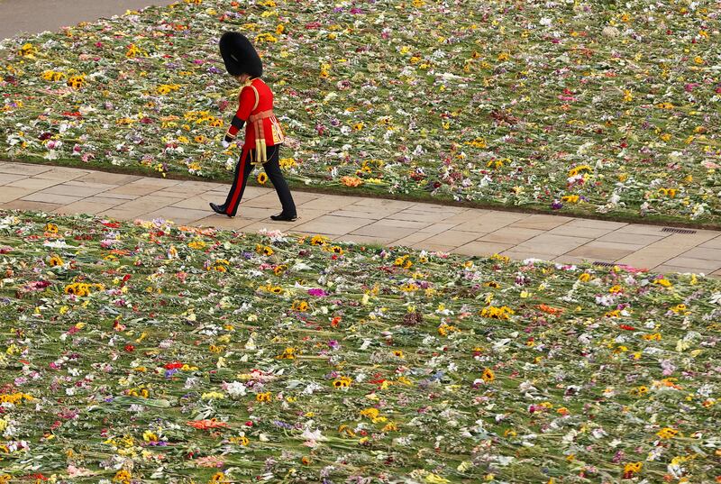 A member of the Coldstream Guards walks past flowers at St George's Chapel in Windsor Castle. AP