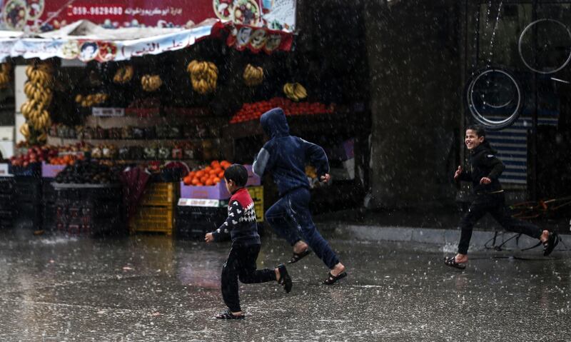 Children run in flooded street on a rainy day in al-Amal (hope in Arabic) neighbourhood of Beit Lahia in the northern Gaza Strip.  AFP