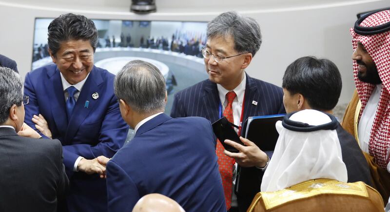 epa07681571 South Korean President Moon Jae-in (C) shakes hands with Japanese Prime Minister Shinzo Abe (L) on the second day of the G20 summit in Osaka, Japan, 29 June 2019. It is the first time that Japan hosts a G20 summit. The summit gathers leaders from 19 countries and the European Union to discuss topics such as global economy, trade and investment, innovation and employment.  EPA/YONHAP SOUTH KOREA OUT