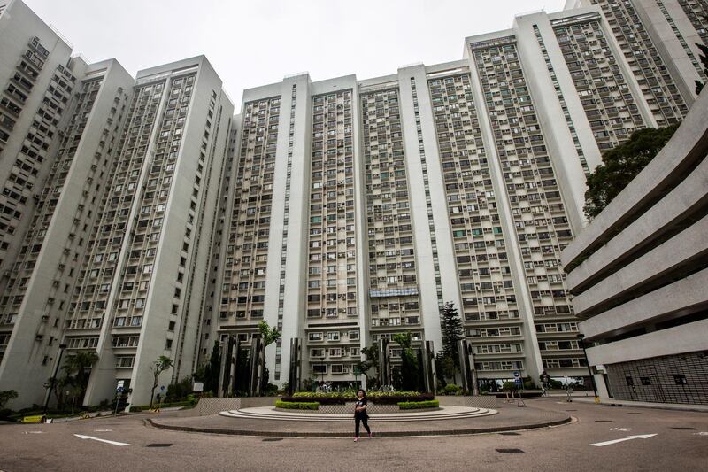 This picture taken on May 25, 2017 shows a resident (C) walking across the road in the Wonderland Villas hilltop residential complex in the Kwai Fong district of Hong Kong. 
Red-whiskered bulbuls start chirping around 5:00 am at Wonderland Villas, a hilltop complex in leafy northern Hong Kong whose own history charts the city's political, economic and social fortunes. Prices at Wonderland have risen, waned and risen again, as Hong Kong property has swung through boom and bust to become one of the world's most expensive markets. / AFP PHOTO / Isaac LAWRENCE / TO GO WITH Hong Kong-China-Britain-lifestyle-property-construction-urban-planning, FEATURE by Elaine YU