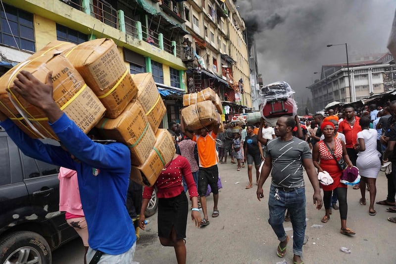 People carry boxes as they salvage goods from a seven-storey building that was on fire at the Balogun Market in Lagos, Nigeria. AFP
