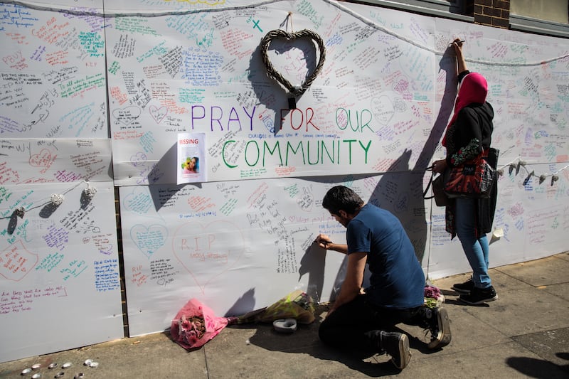 People writing tributes and messages of condolence for the victims on a wall near the site.  Getty Images