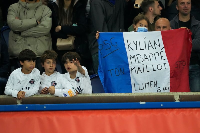 Fans hold a French flag with a message that reads "Kylian Mbappe, your shirt is illuminated". AP